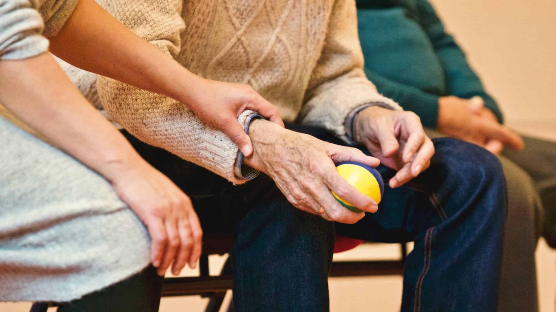 caregiver and elderly person holding a ball